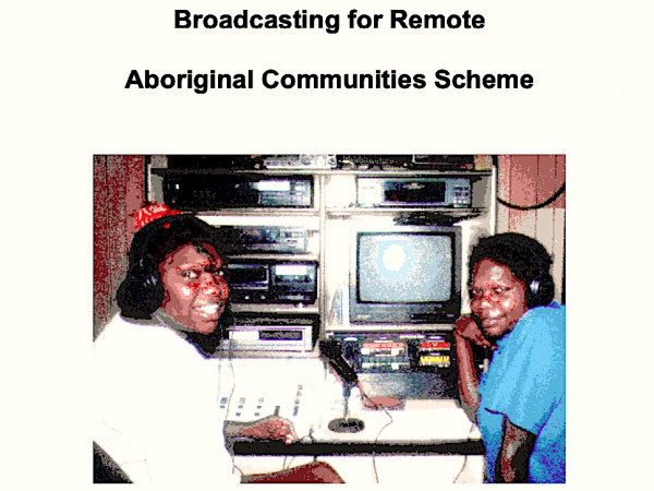 Scanned image of two women sitting and smiling in front of a video equipment, with the caption Brodacasting for Remote Aboriginal Commuinties Scheme.