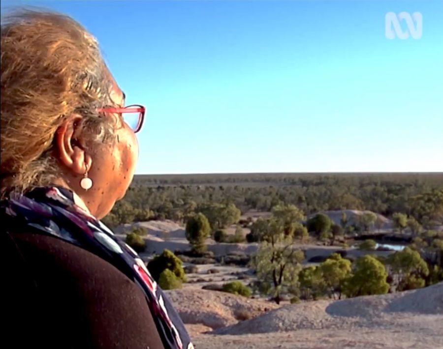 Screengrab from television with woman in foreground looking out over outback..