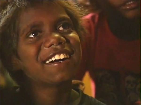 Screengrab. Small indigenous Australian child smiles at camera..