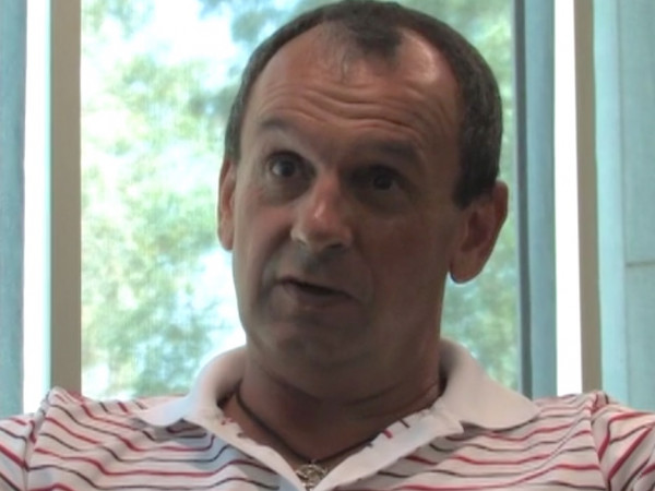Photograph of white male, Alastair Feehan. Wearing a striped polo shirt.