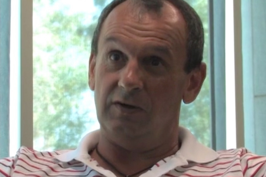 Photograph of white male, Alastair Feehan. Wearing a striped polo shirt.